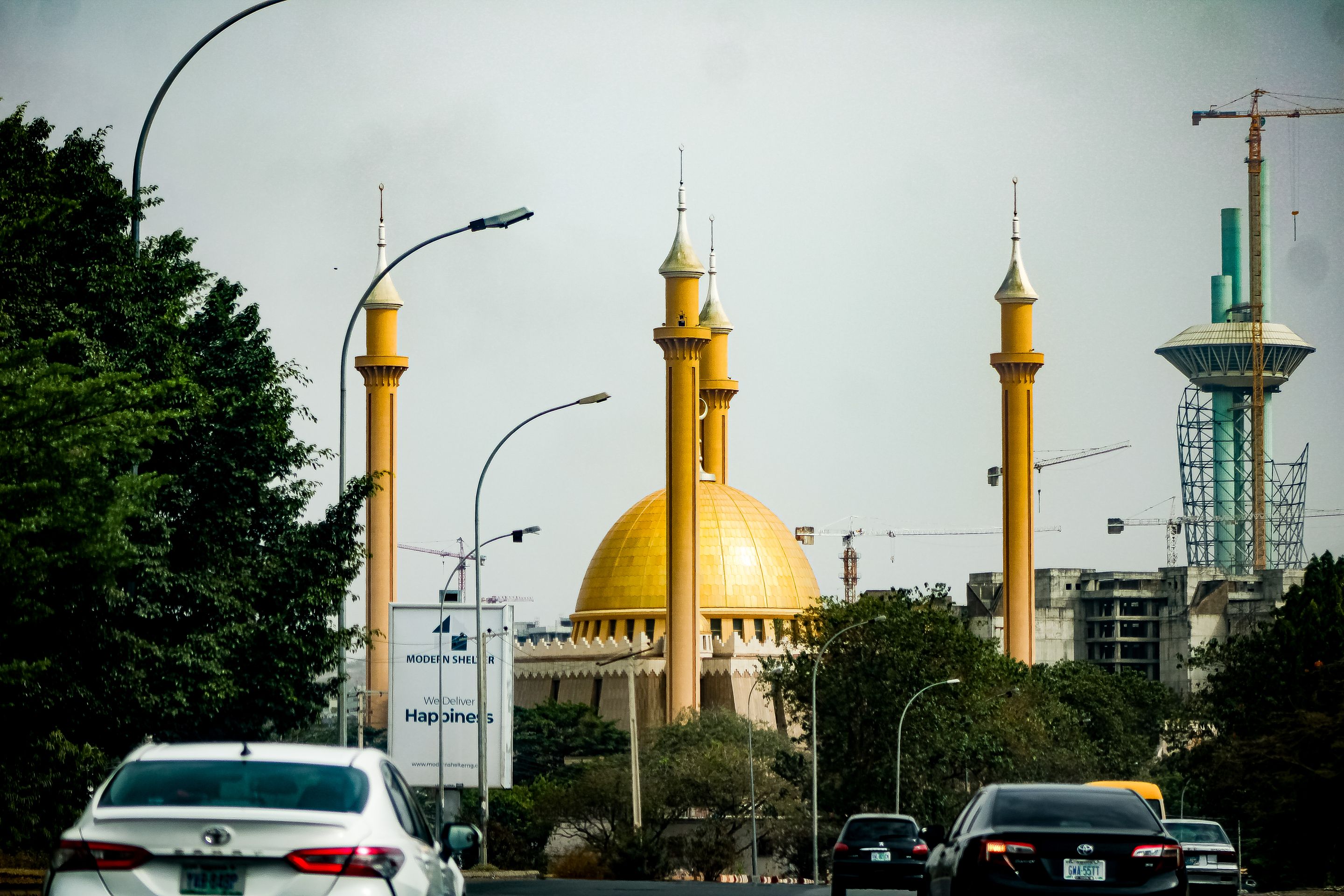 A bustling city street in Abuja featuring the iconic National Mosque and cars in traffic.