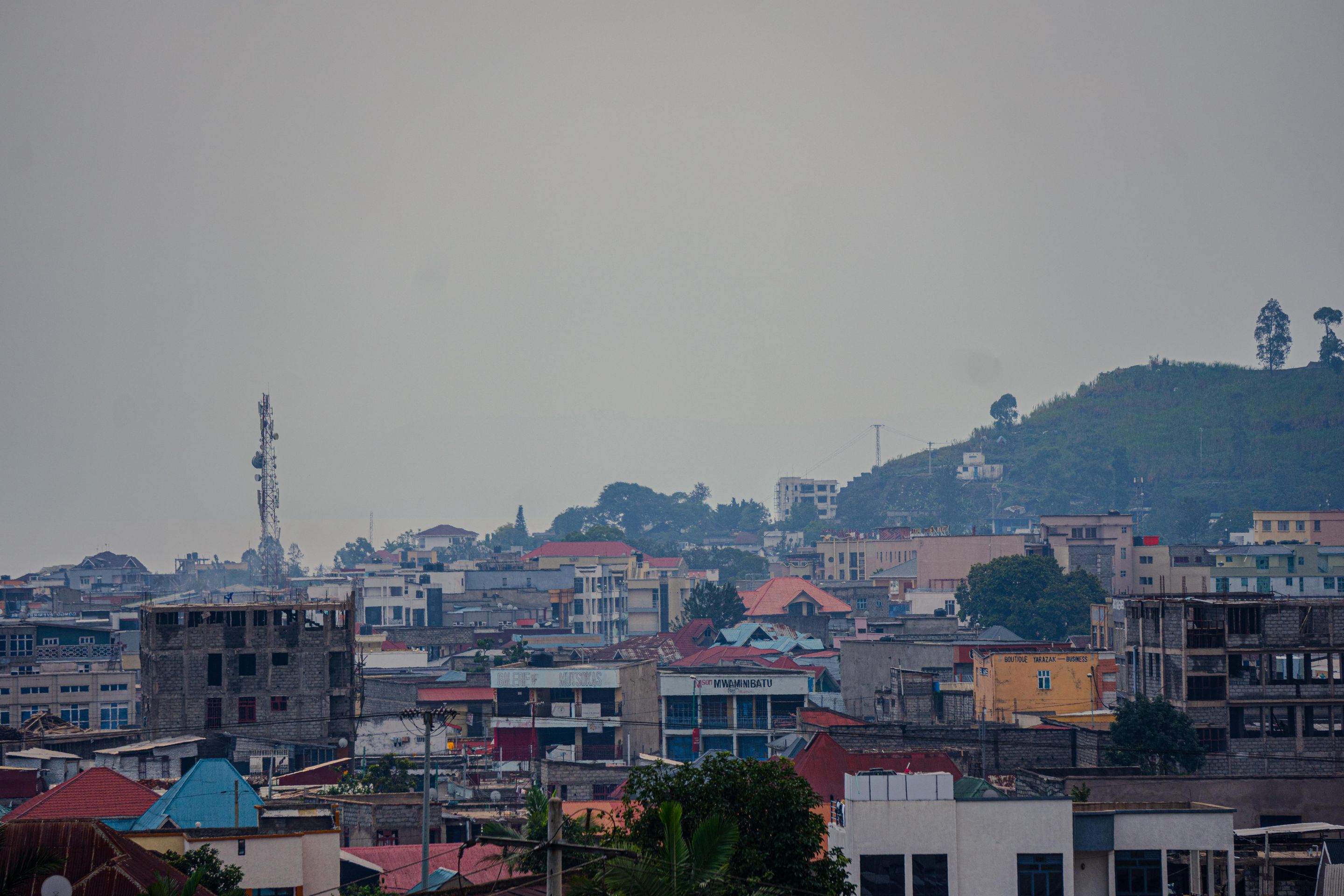 Elevated view of urban buildings with a hill backdrop under overcast skies, ideal for cityscape themes.