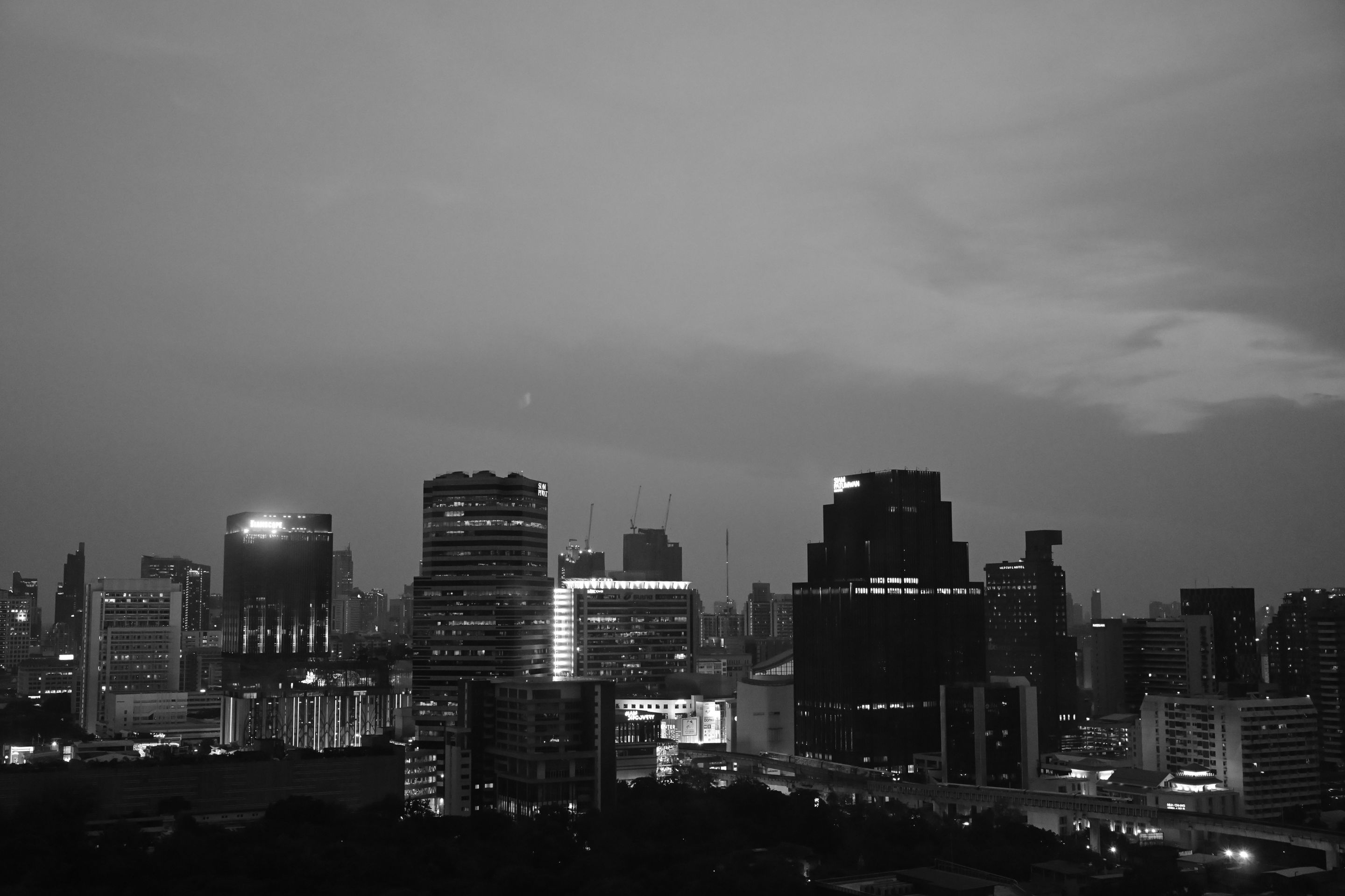 Aerial view of Bangkok's skyline in black and white captures an urban scene at dusk.