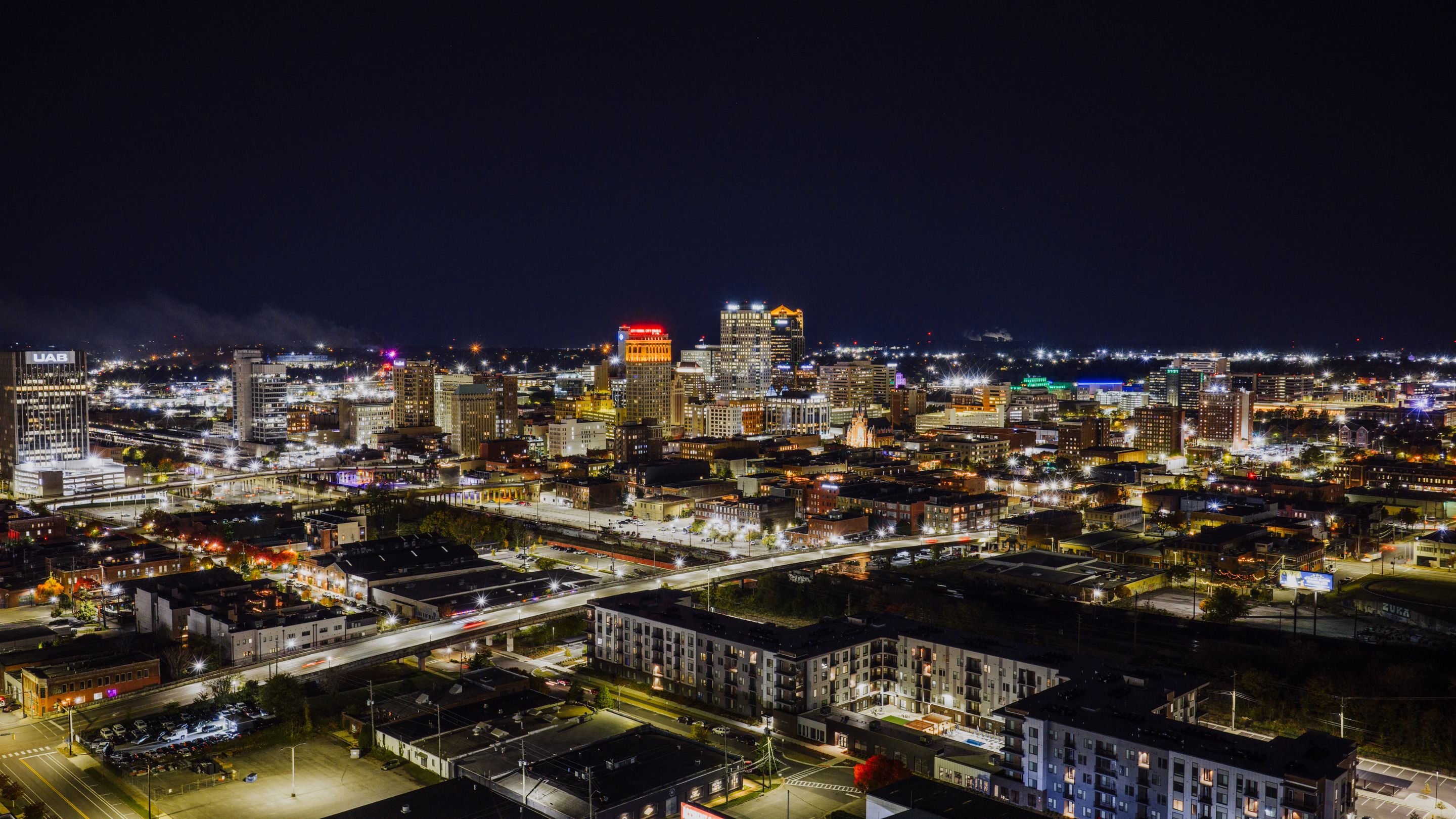 Stunning aerial night view of Birmingham, Alabama with illuminated cityscape and skyscrapers.
