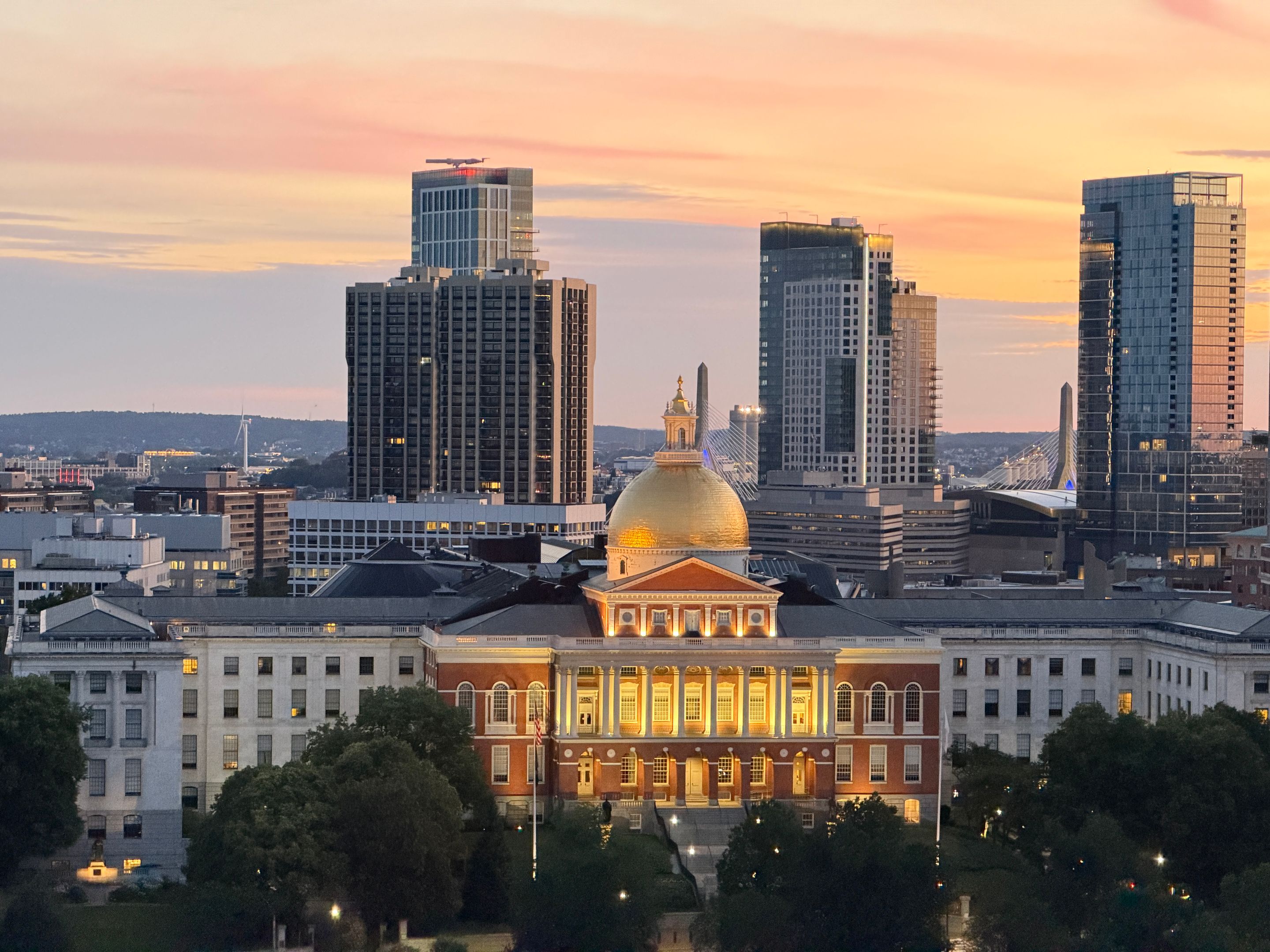 A breathtaking view of Boston's skyline with the Massachusetts State House at sunset, showcasing its iconic golden dome.