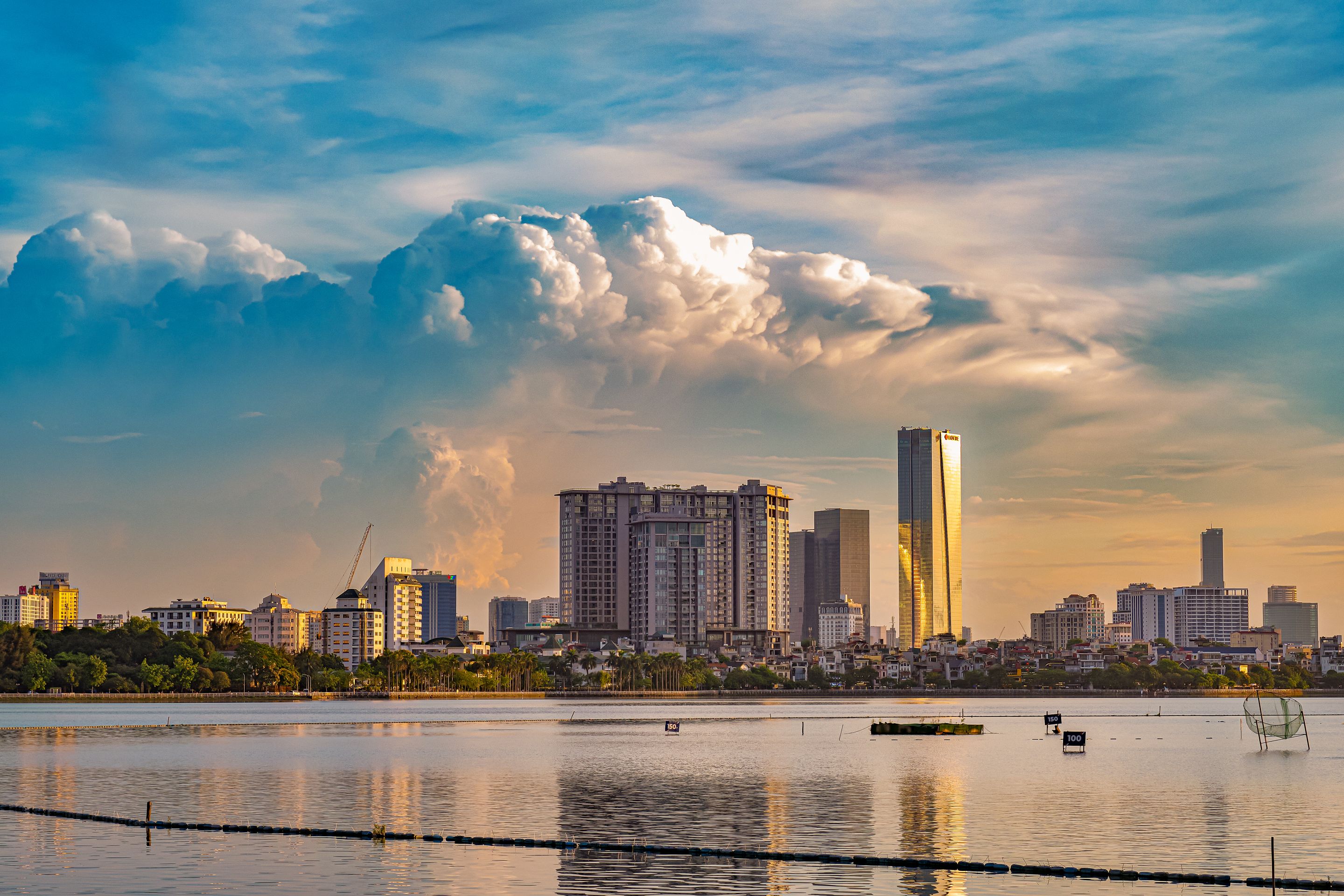 Vibrant sunset over Hanoi's skyline, reflecting beautifully on the calm river waters.