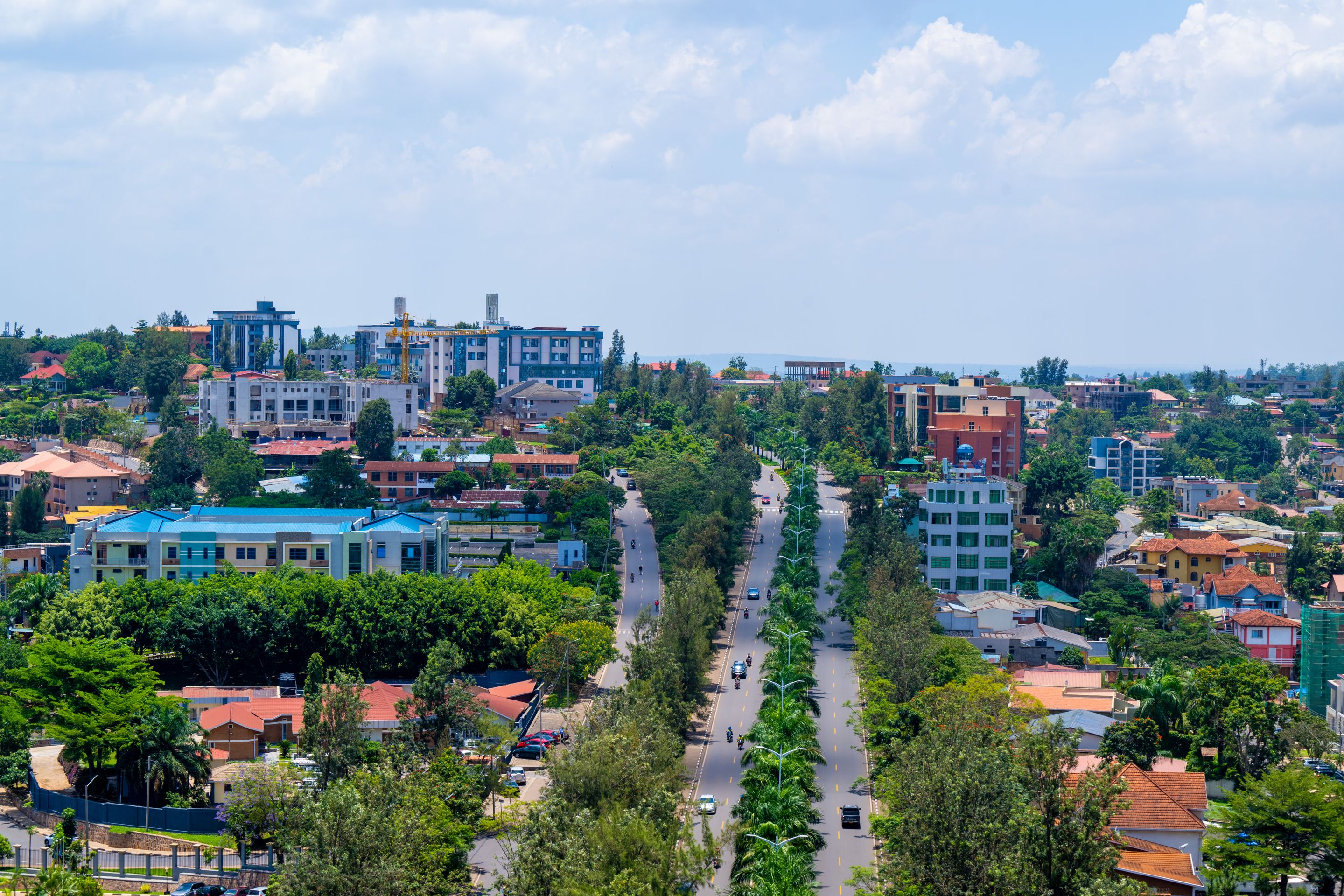 Panoramic view of Kigali cityscape featuring lush greenery and urban development under a sunny sky.