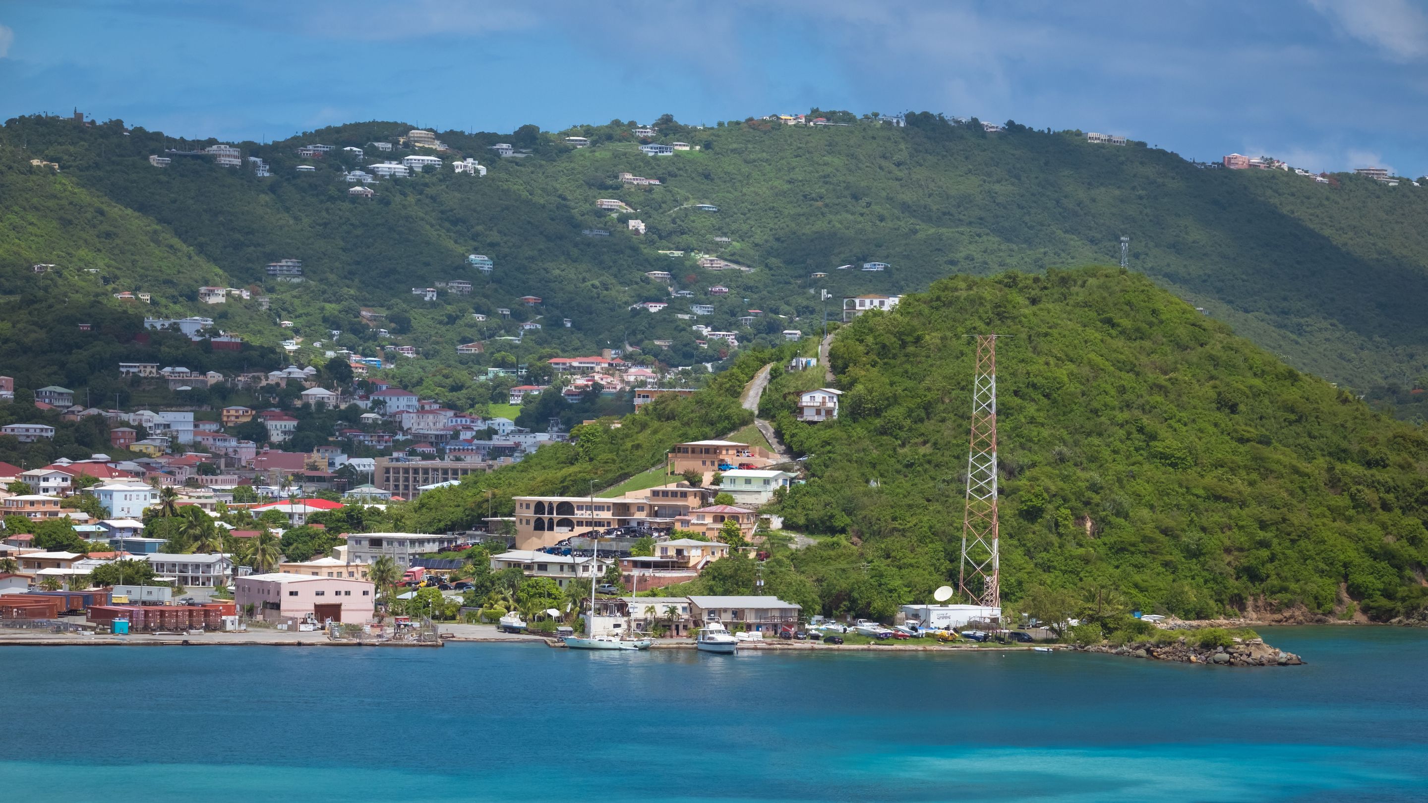 A picturesque coastal scene featuring lush green hills and vibrant turquoise waters.