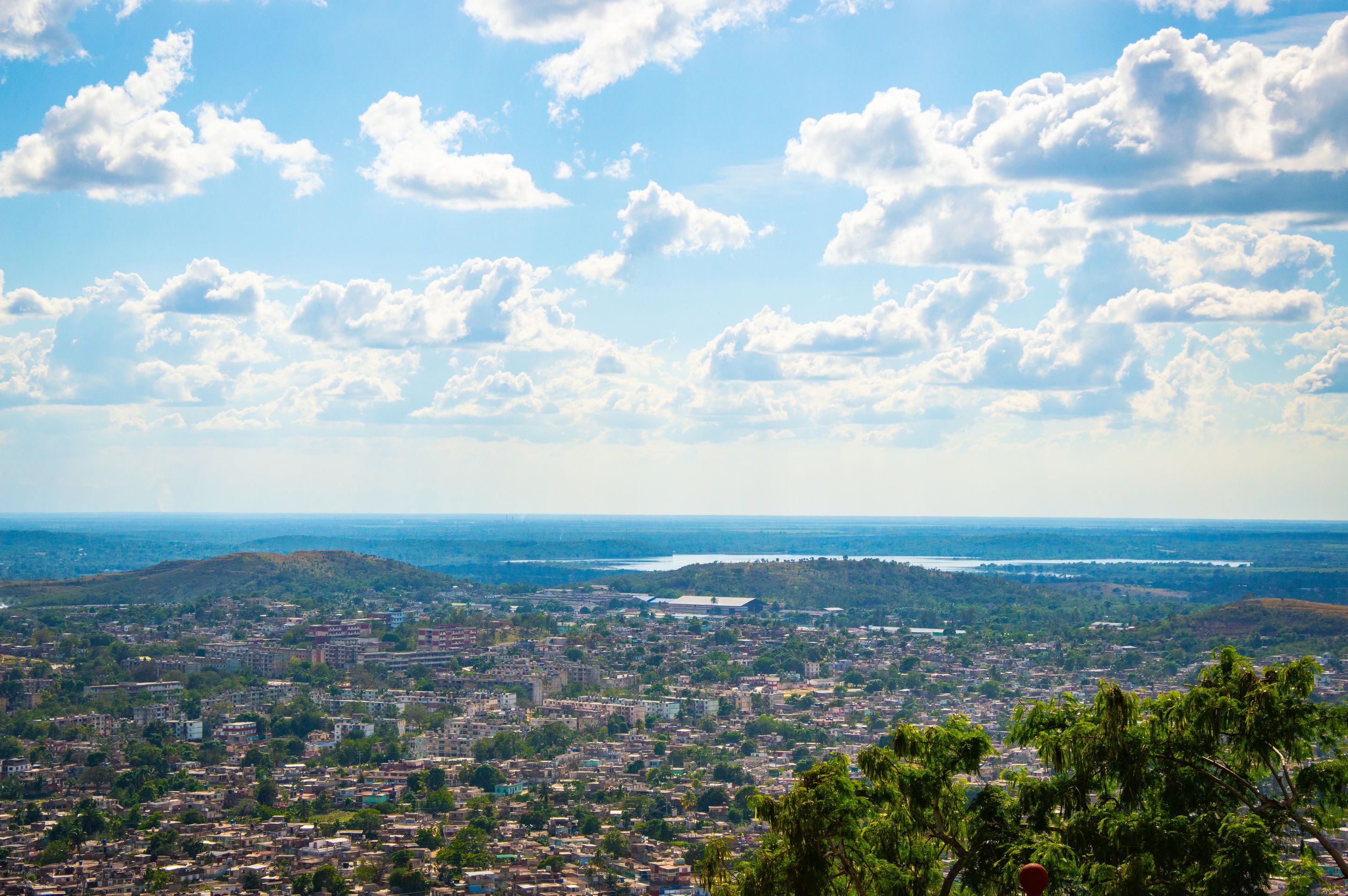 Aerial view of city under a bright blue sky with scattered clouds.