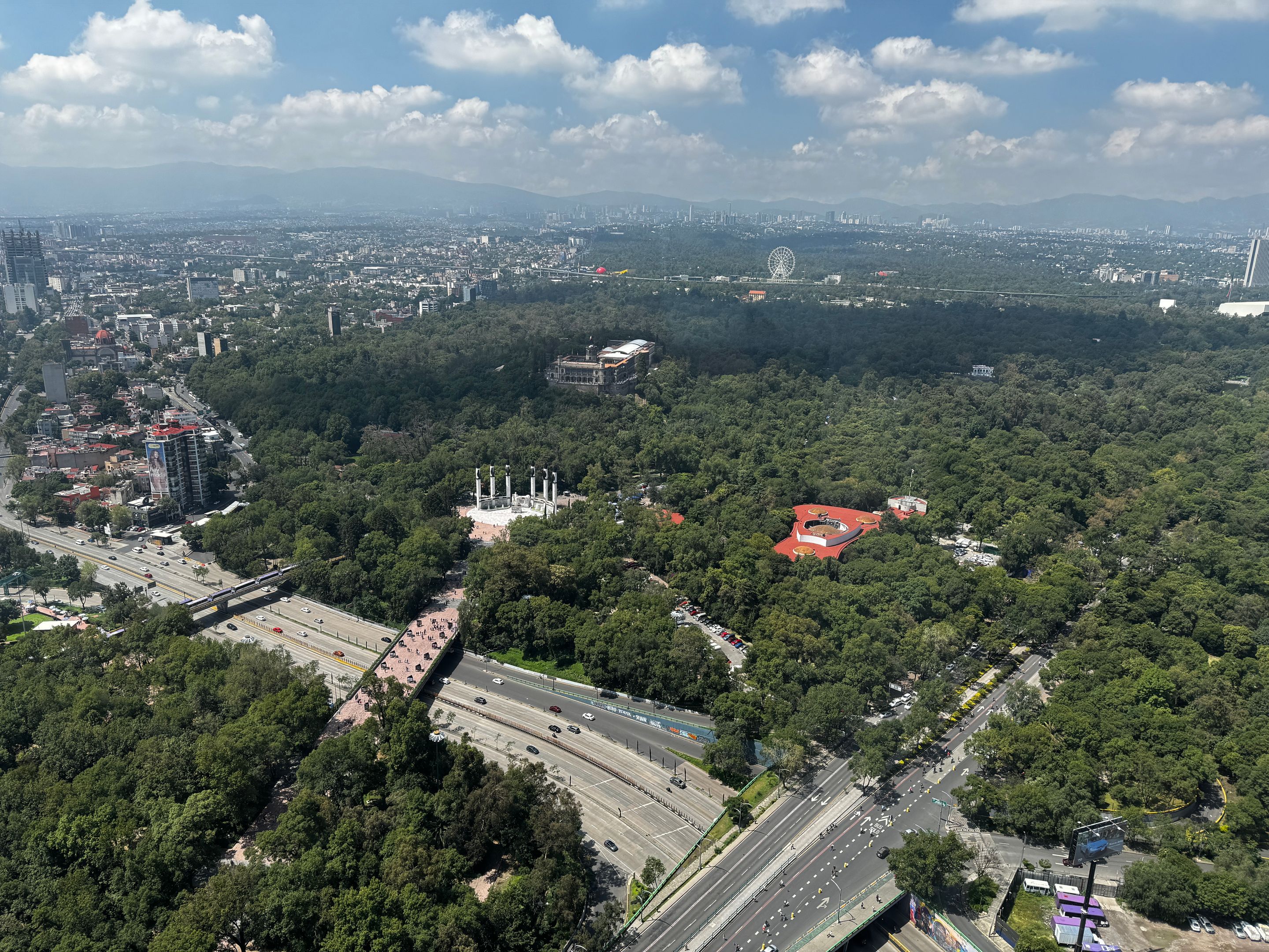 A stunning aerial view of Chapultepec Park with cityscape and mountains in the background.