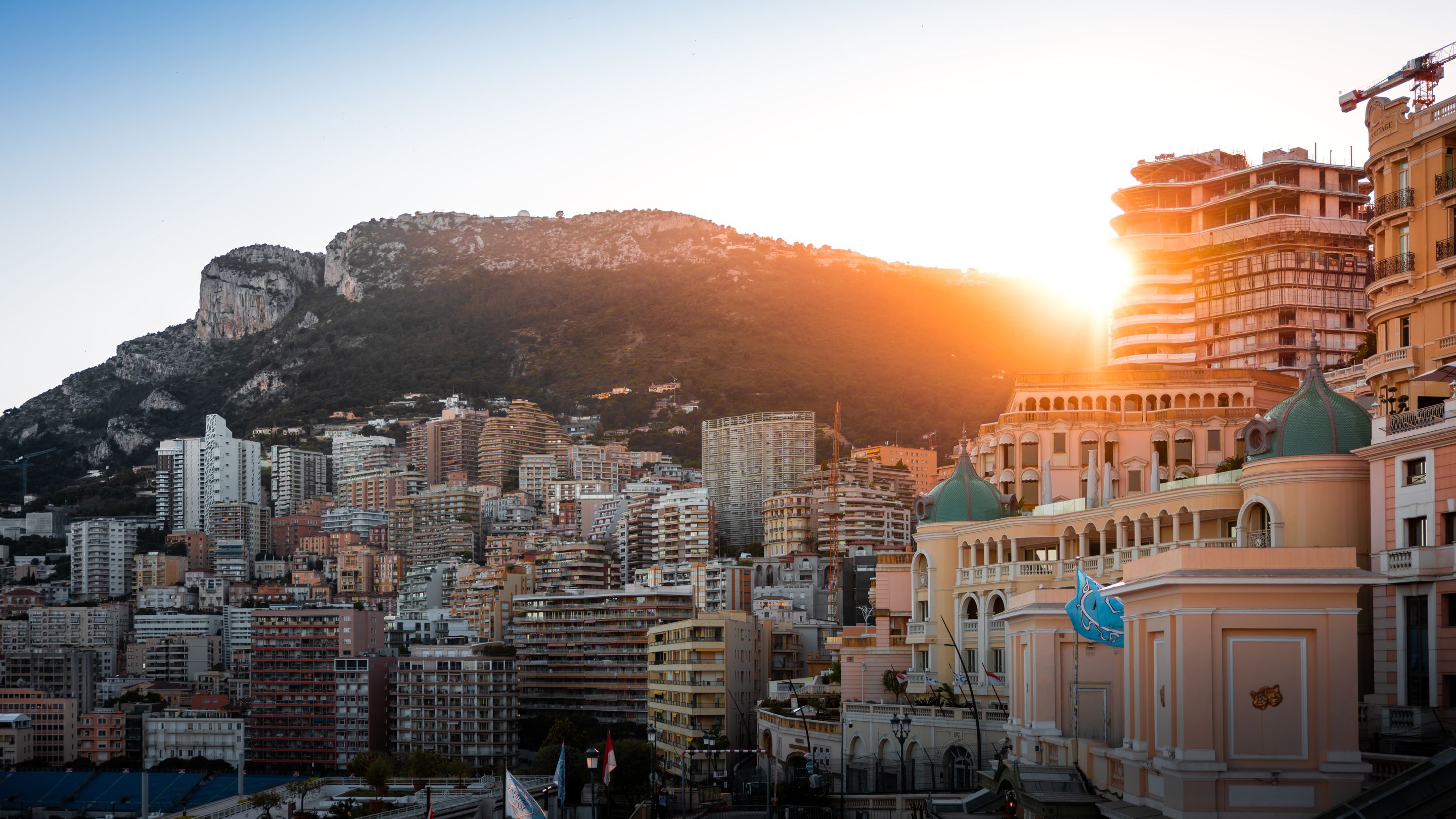 Stunning sunset view of Monaco's cityscape with mountains in the background.