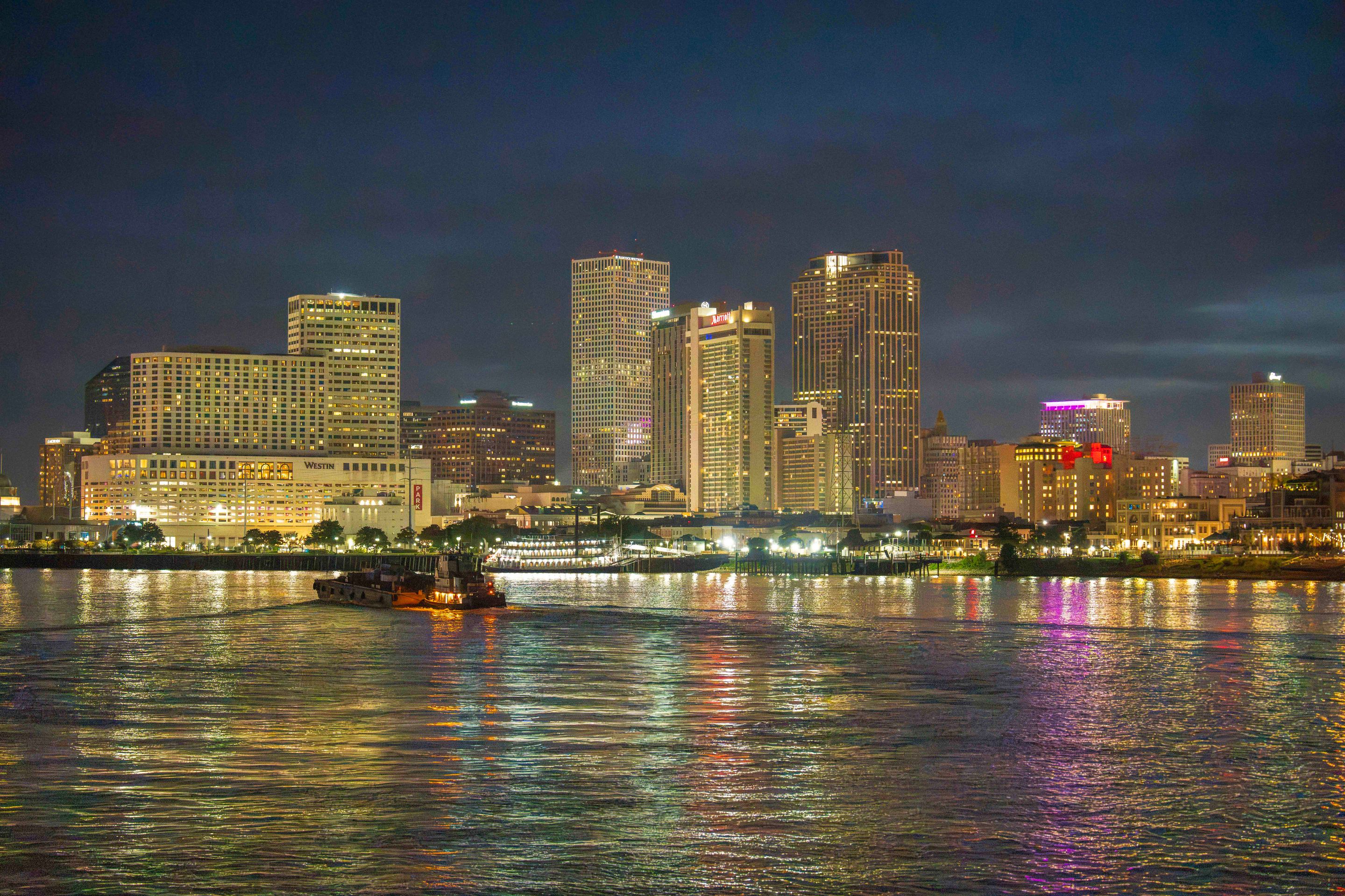 A breathtaking night skyline view of New Orleans with vibrant reflections on the Mississippi River.