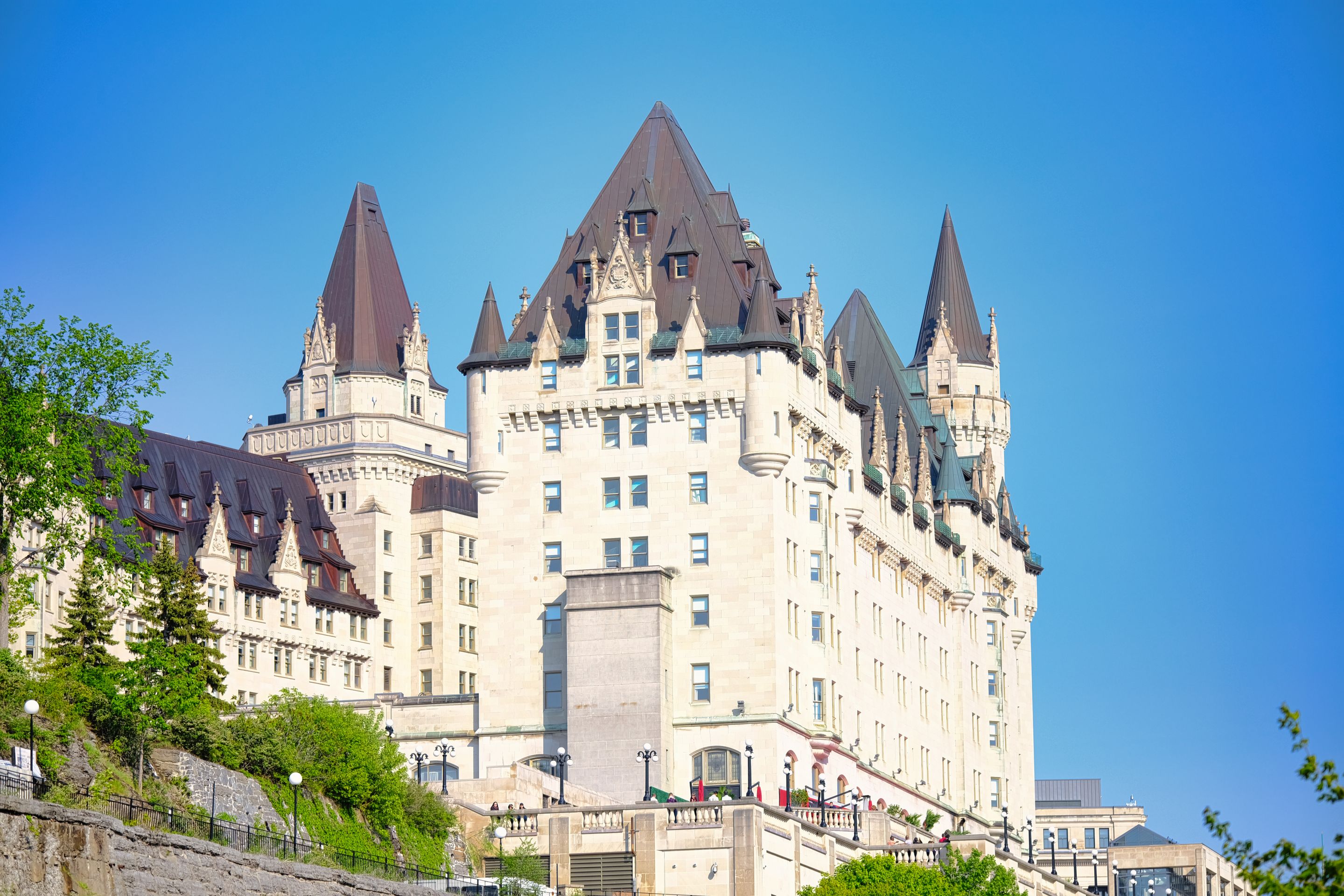 Sunlit view of the iconic Fairmont Château Laurier in Ottawa, Canada, against a clear blue sky.