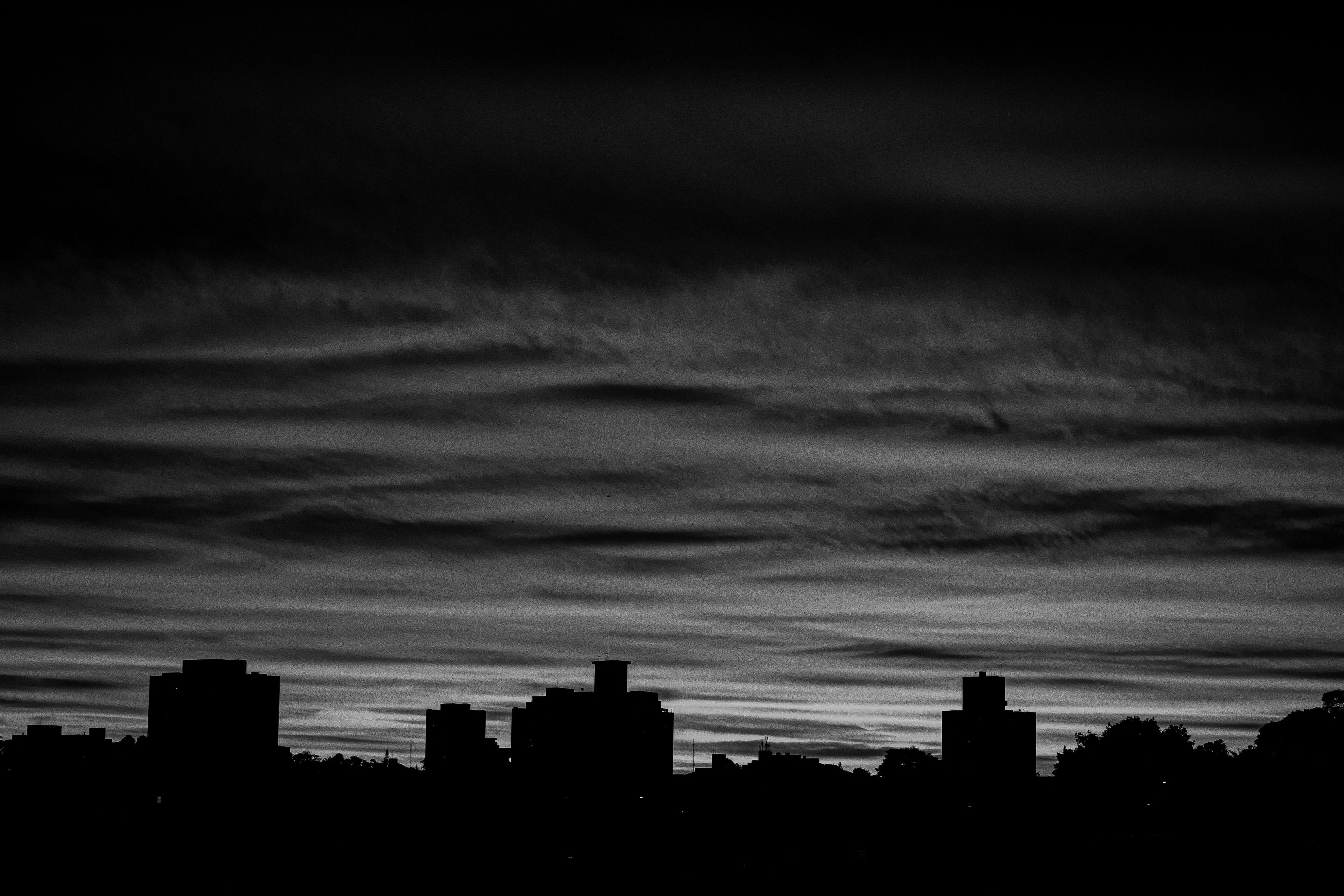 A dramatic black and white city skyline silhouette with a moody twilight sky.