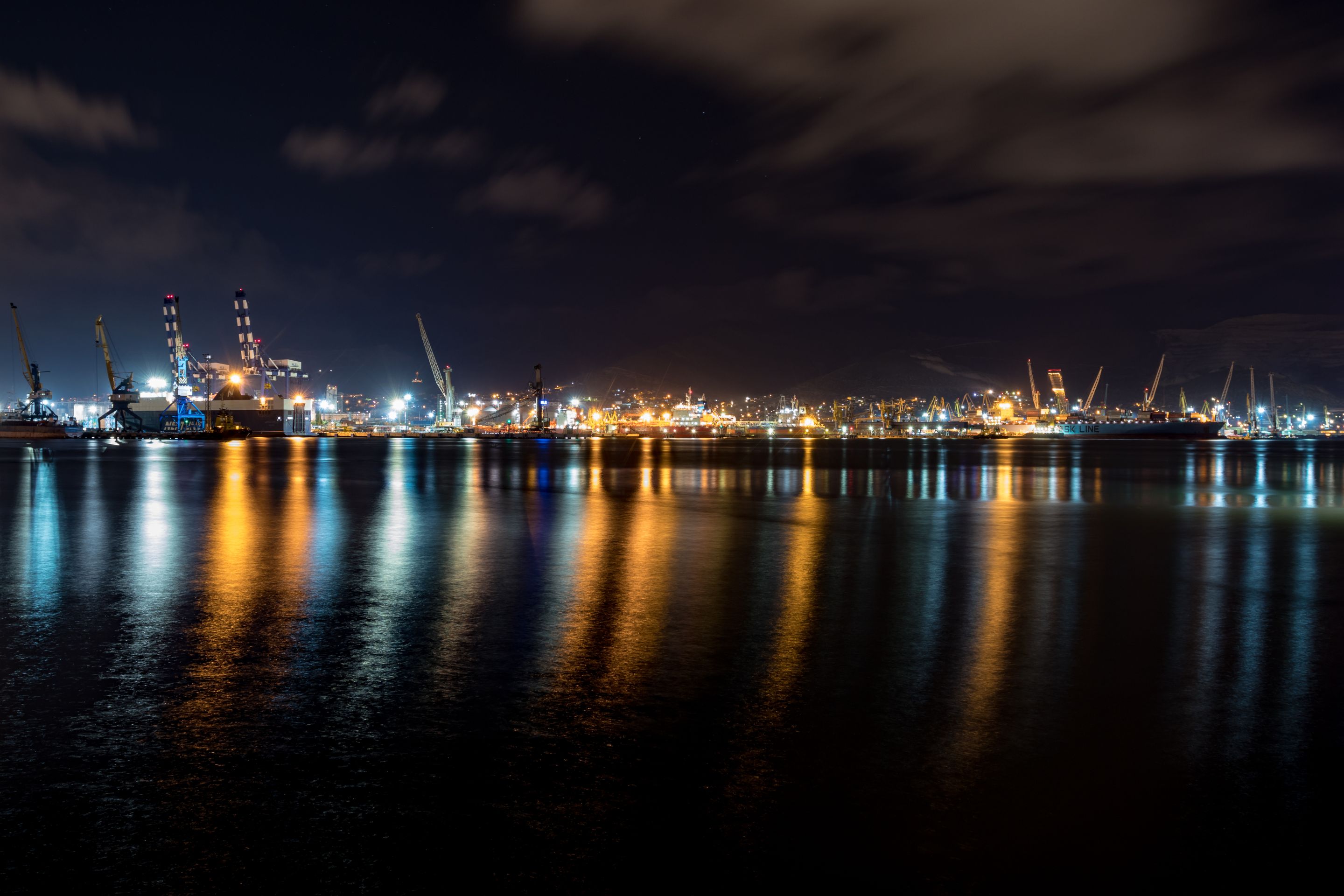 Explore the beauty of a harbor illuminated at night, showcasing vibrant reflections on the calm water.