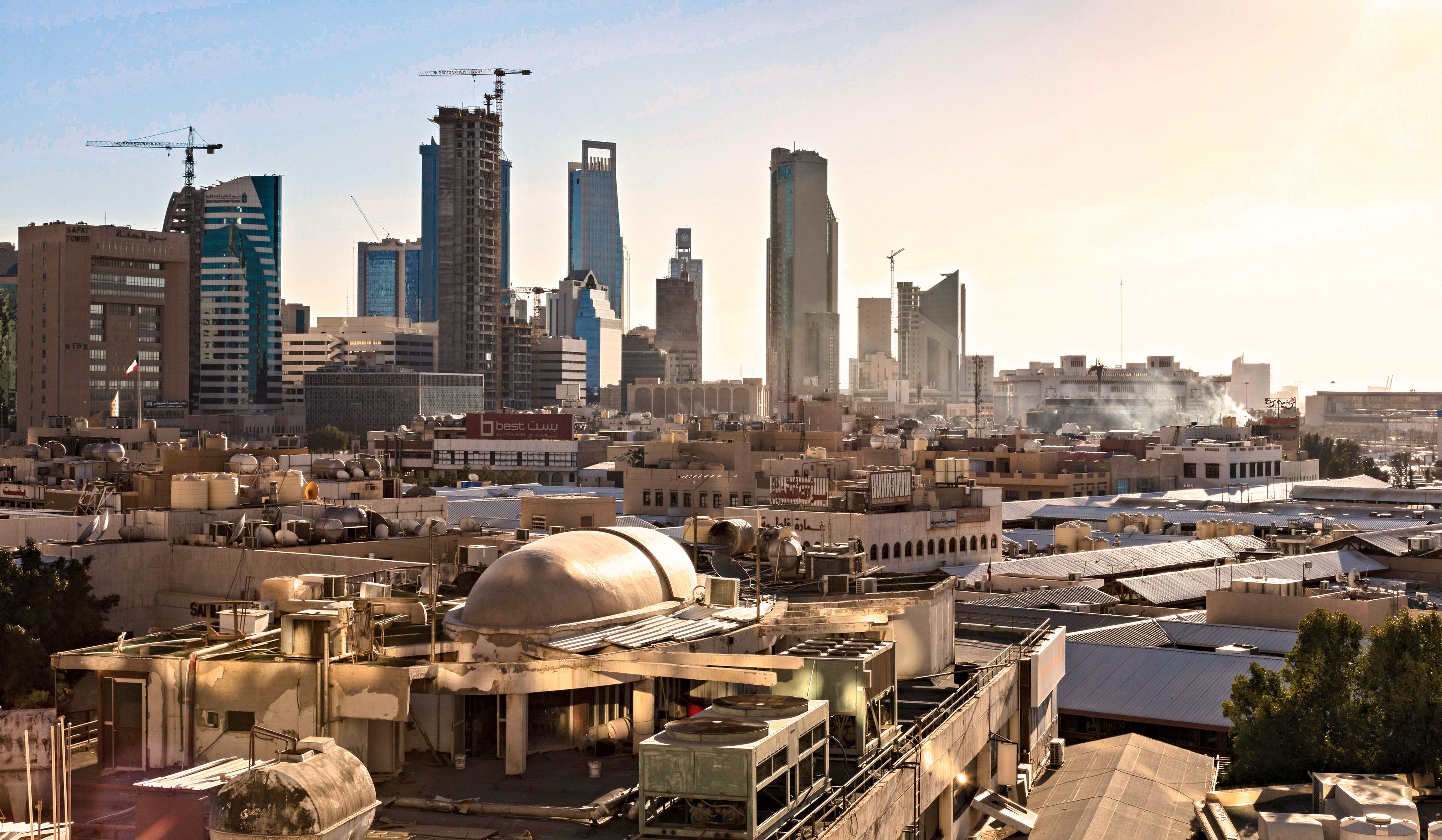 Skyline of Riyadh, Saudi Arabia featuring modern skyscrapers and construction cranes at sunset.