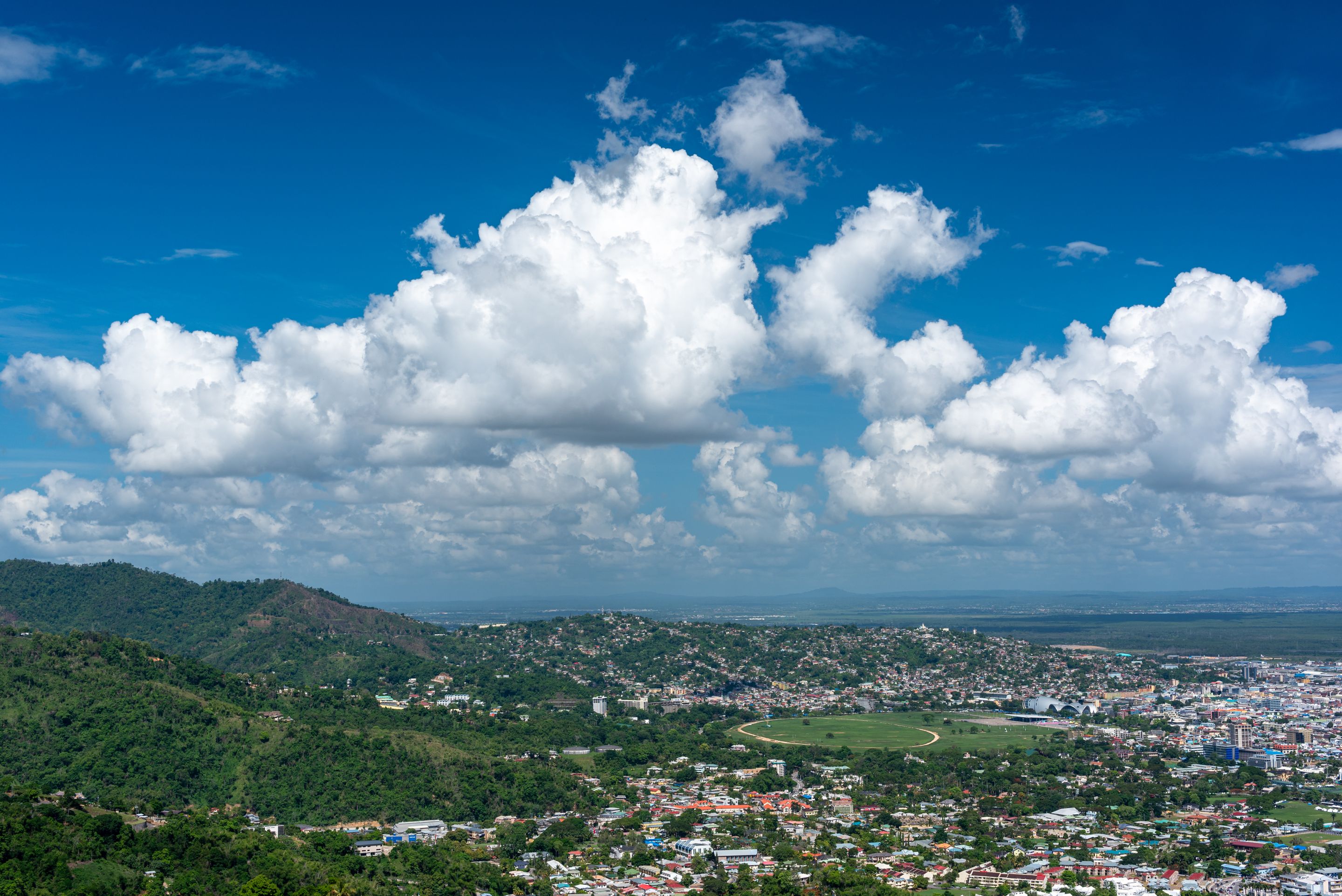 Breathtaking aerial view of Port of Spain with lush hills and clear skies, showcasing Trinidad's vibrant cityscape.