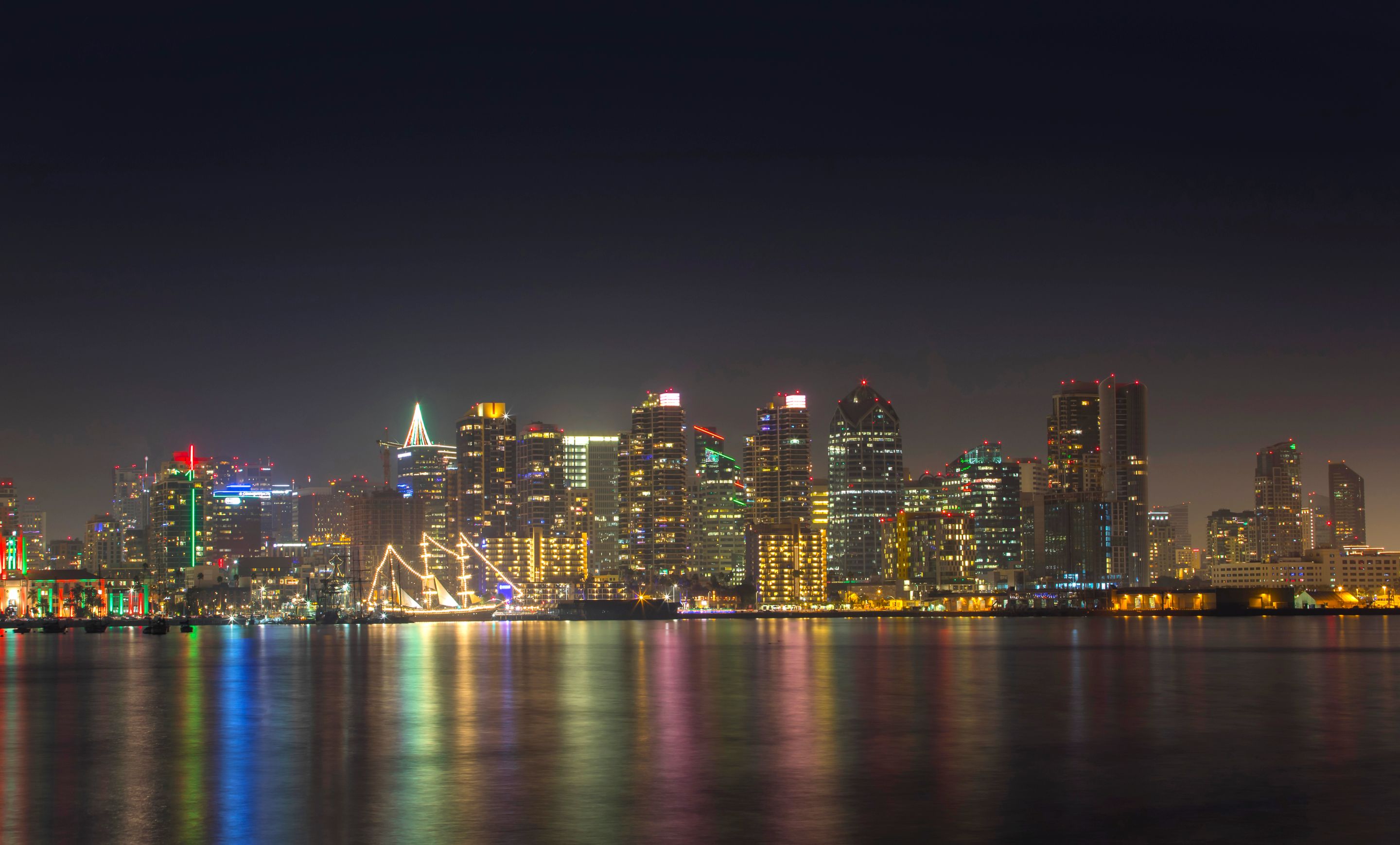 A serene night view of San Diego's illuminated skyline reflecting on calm water.