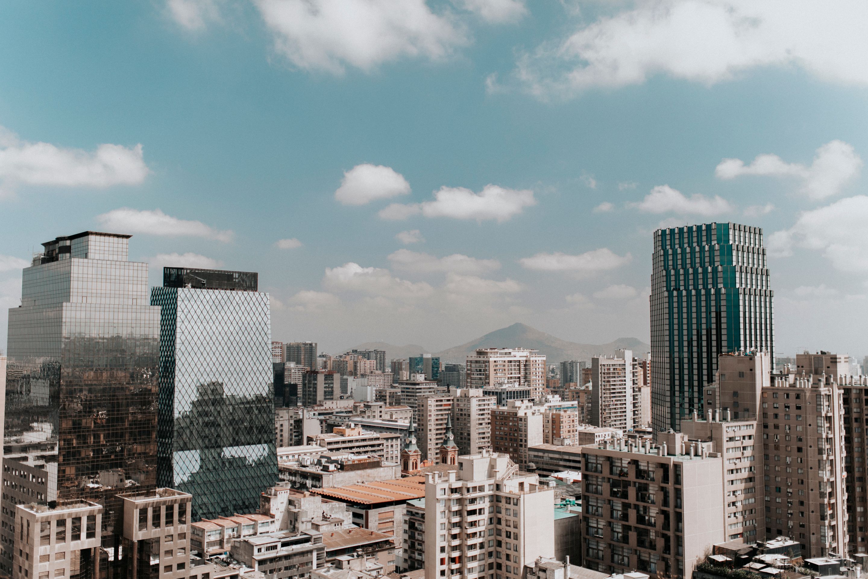 View of Santiago's skyline featuring modern architecture and surrounding mountains under a clear sky.