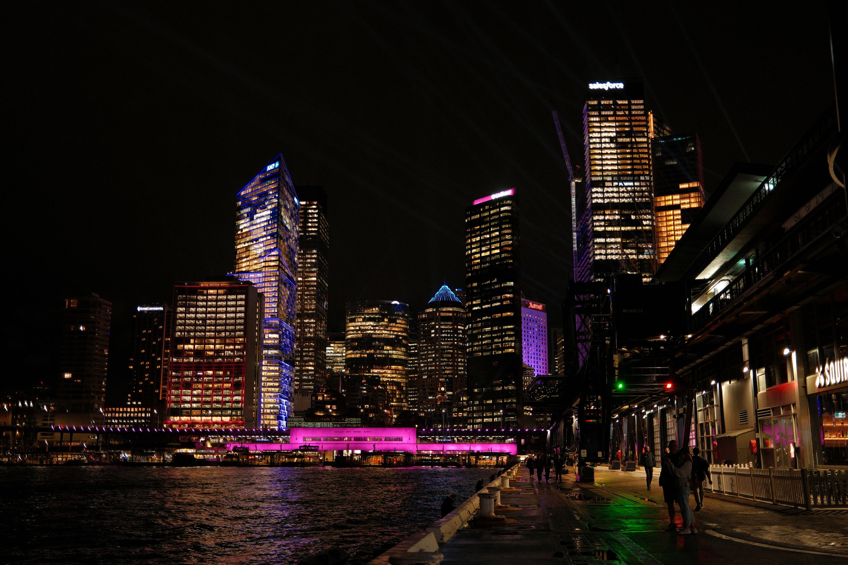 Stunning night view of Sydney's illuminated skyline with vibrant lights reflecting on water.