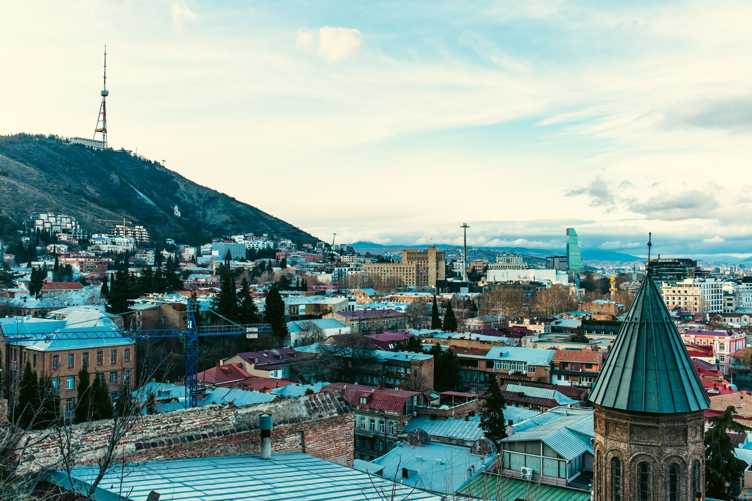 Aerial view of Tbilisi showcasing iconic landmarks and vibrant cityscape under a clear sky.