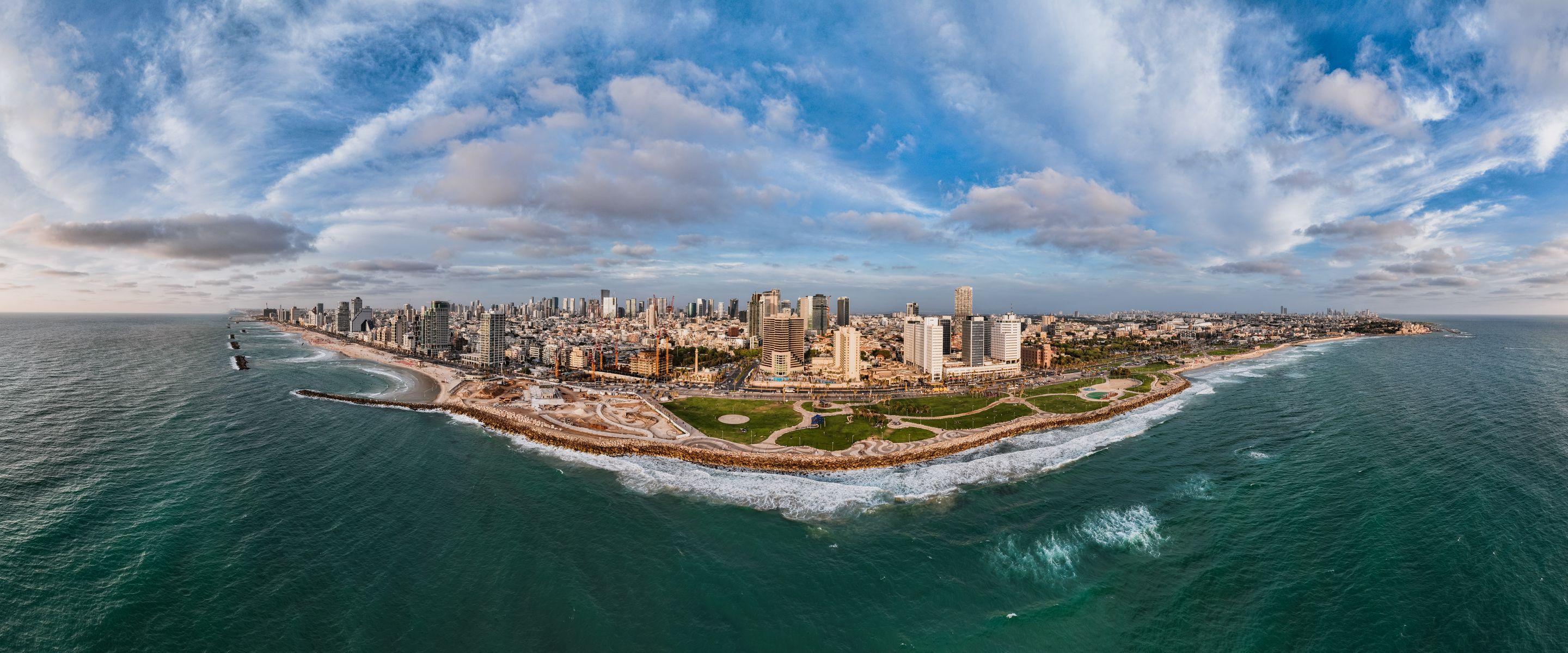 Panoramic aerial view of Tel Aviv's coastline showcasing urban skyline and Mediterranean Sea.