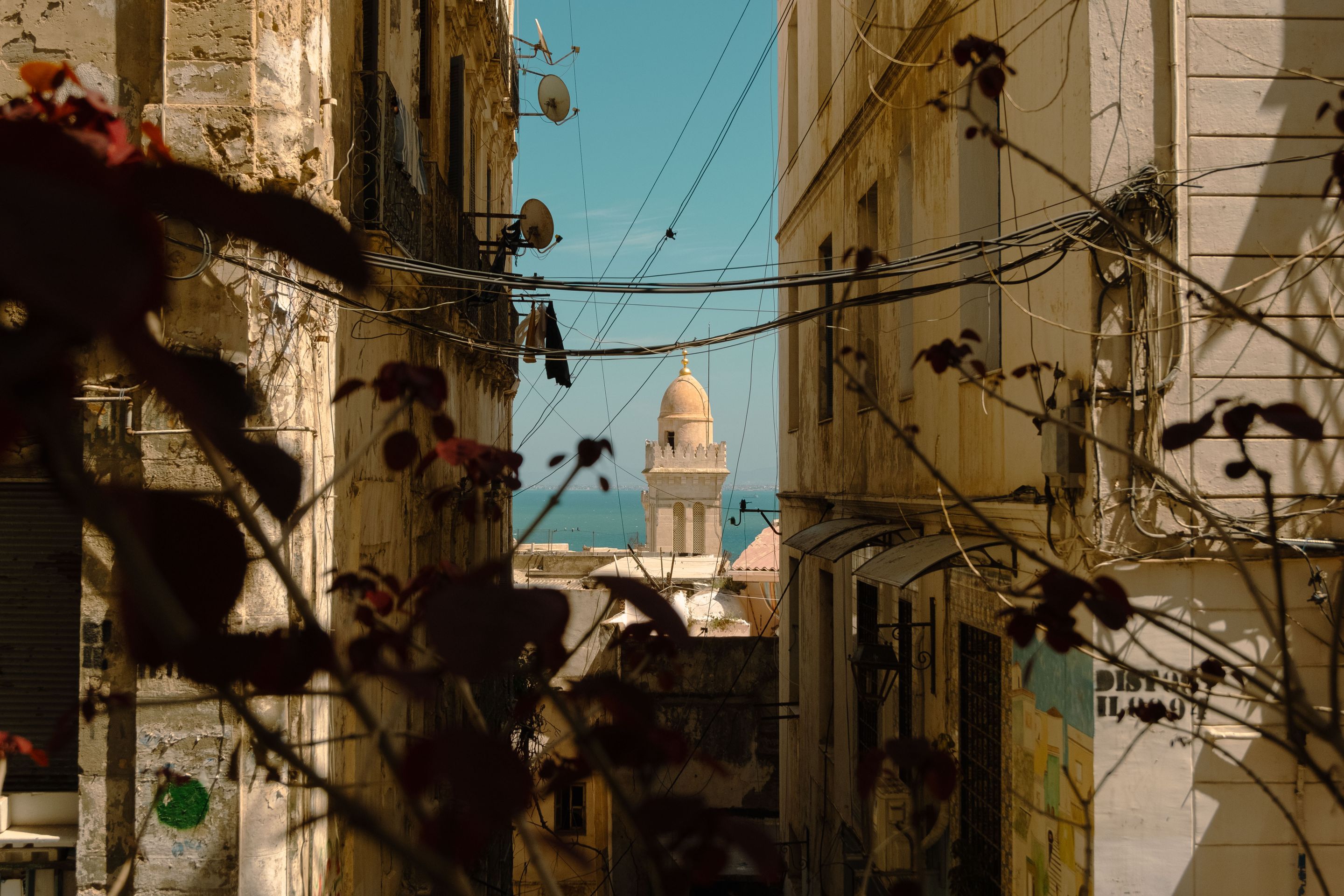 A captivating view through urban architecture to a minaret by the coast. Tranquil setting with cultural charm.