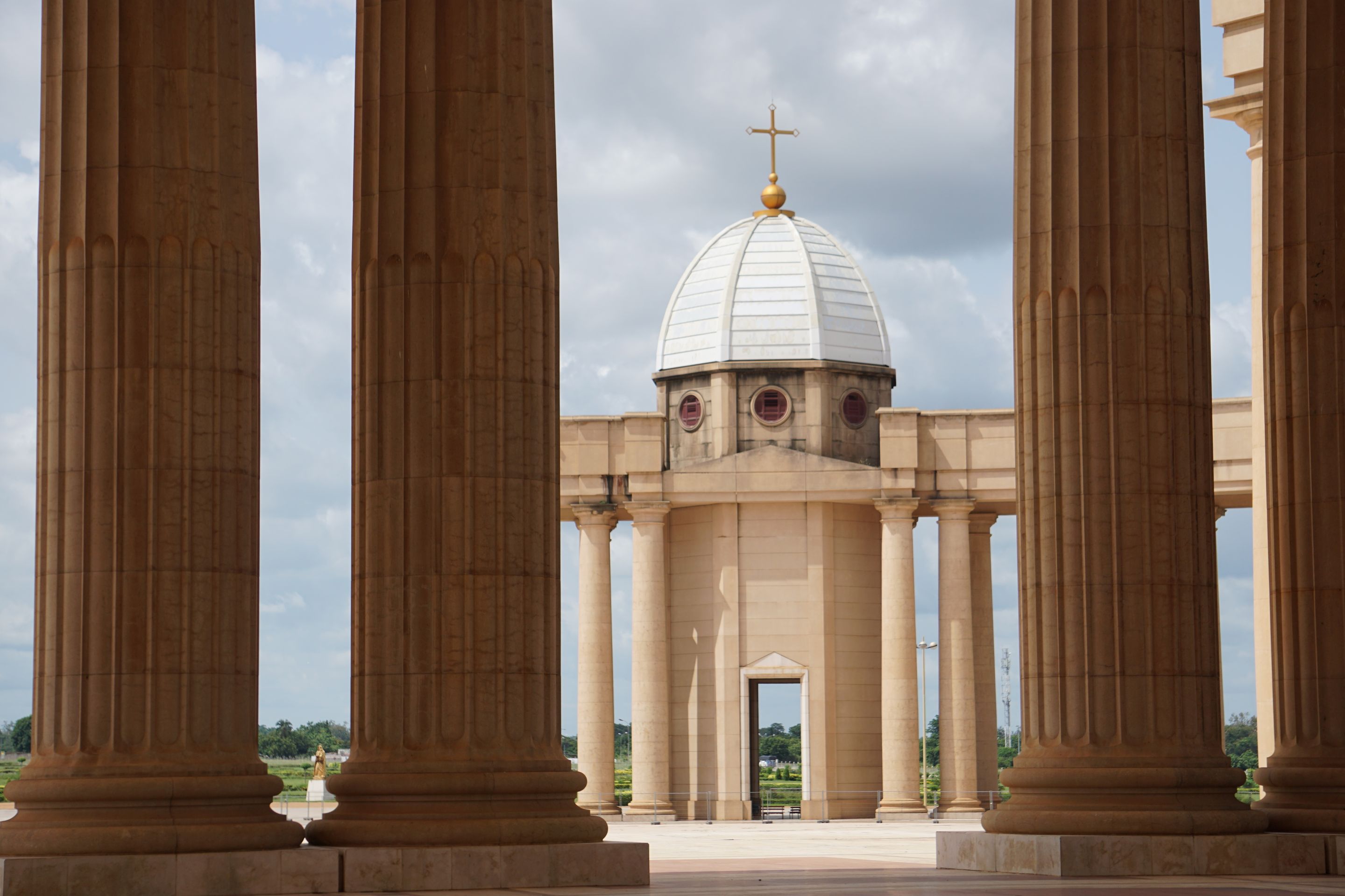 View of Basilica of Our Lady of Peace in Yamoussoukro, showcasing majestic columns and architecture.